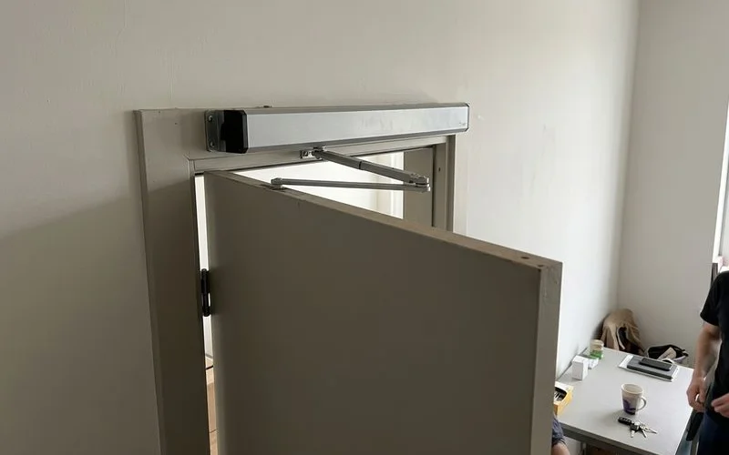 Swing door operator arm above a door frame
