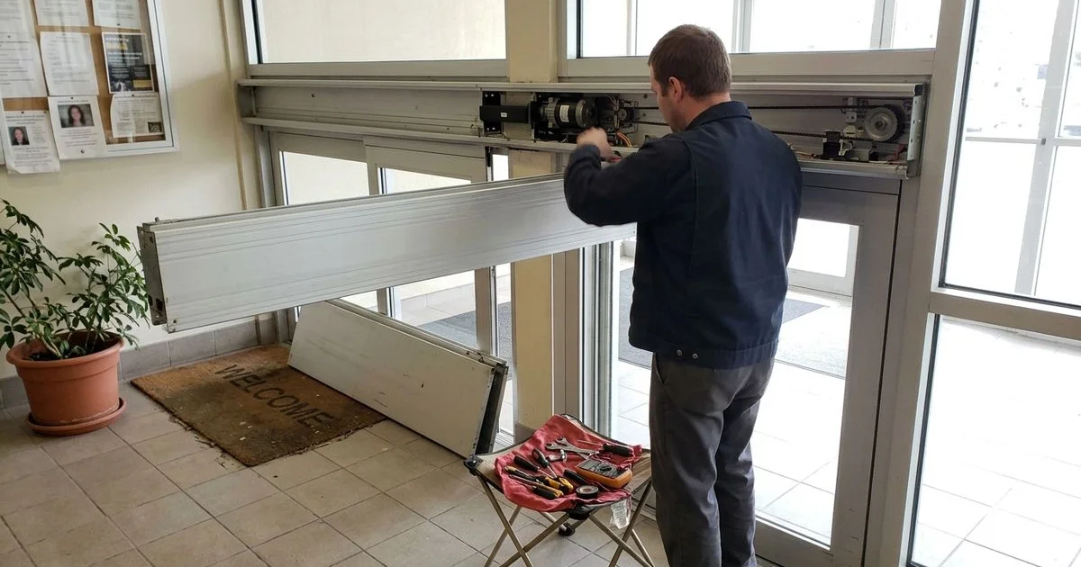 Technician performing scheduled maintenance on an automatic door